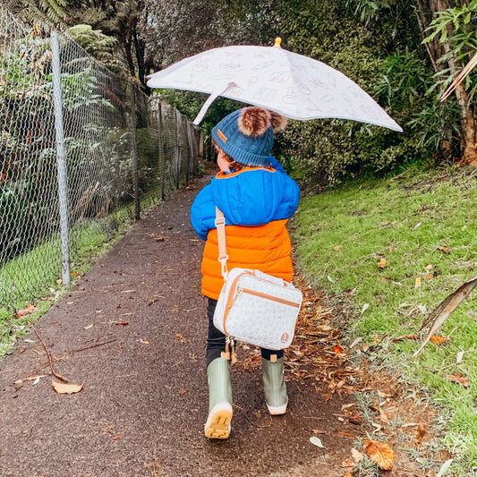 Kids holding a classic pattern umbrella and carrying a lunch bag for rainy day adventure - Stick Hunters