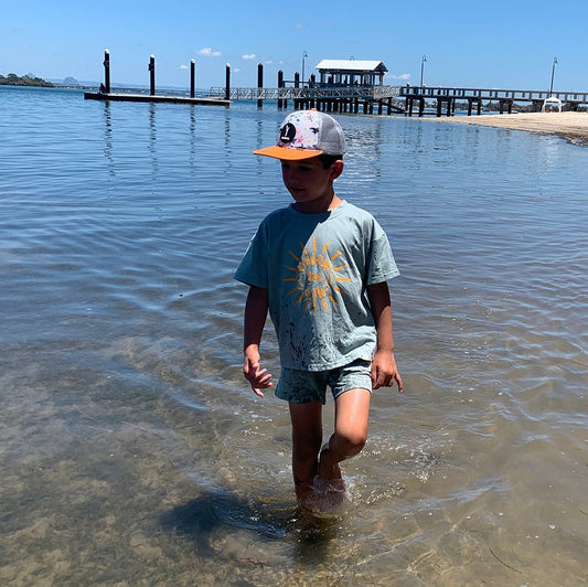 Boy walking along the beach wearing trucker hat with sea animals print - Stick Hunters