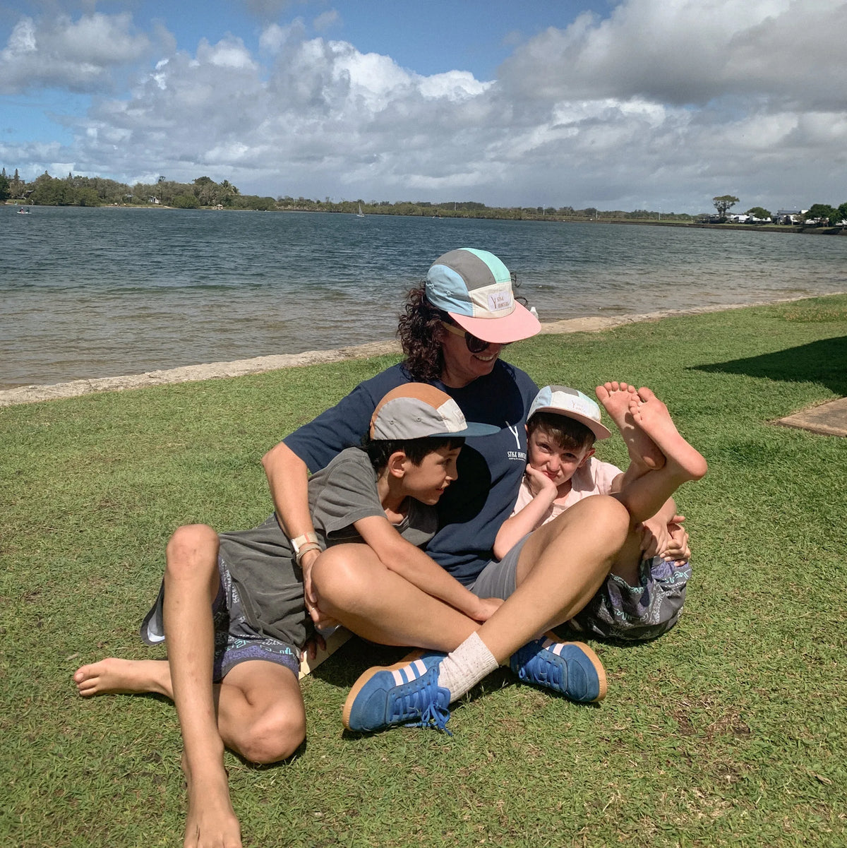 Mum and boys playing on the grass wearing a matching quick dry 5 panels hat in nylon fabric. 